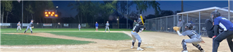 School kids playing baseball at night