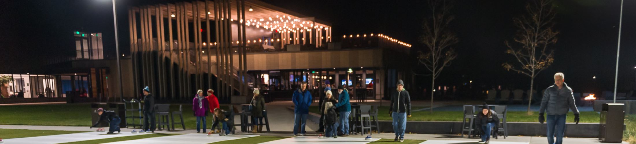 Groups of people playing Pub Curling in front of Three One Six Bar and Grill at night