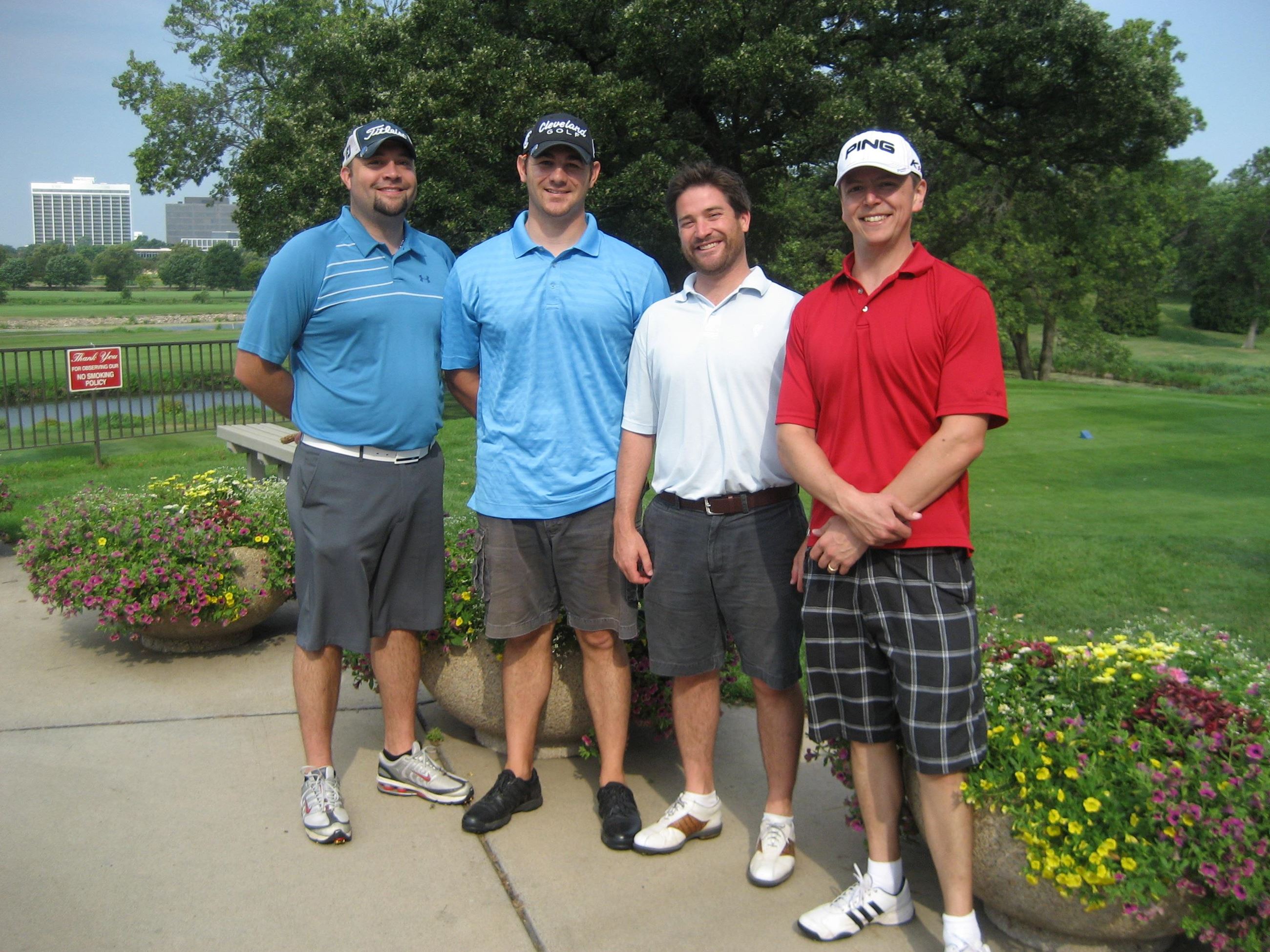 Several Golfers Stand Beside Flower Planters